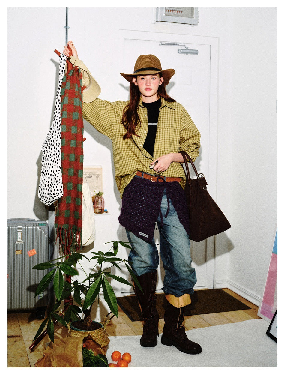 Front view of a model wearing a yellow checked shirt over a black top, with jeans and a purple knit wrap.
