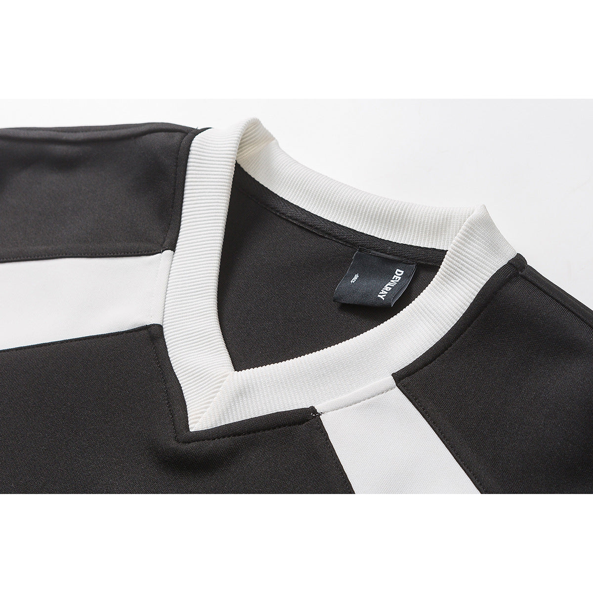 Close-up of a black shirt's white ribbed V-neck collar and contrasting shoulder panels.