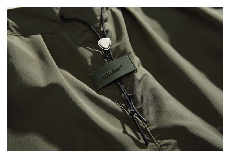 Close-up of the olive shorts' black drawcord, cord lock and attached CITY BOY tag.