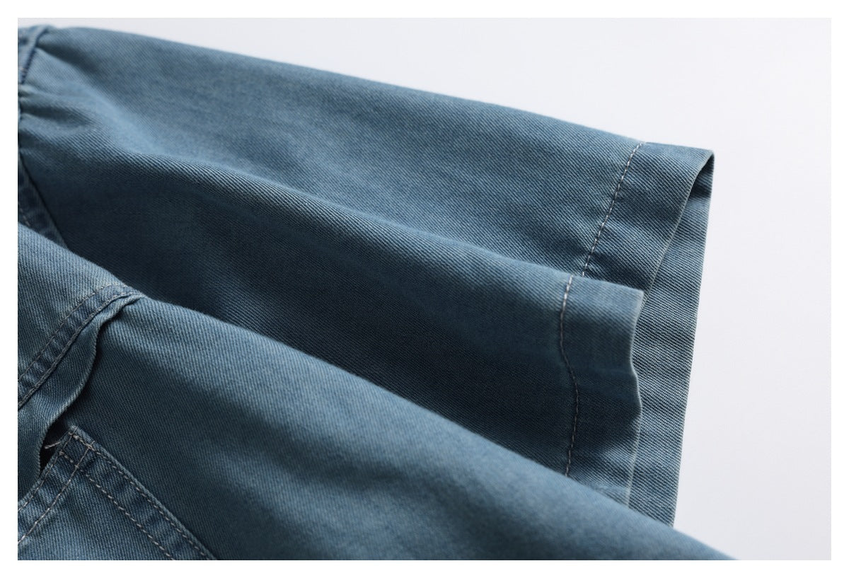 Close-up of the short sleeve and stitched cuff of a blue denim shirt.