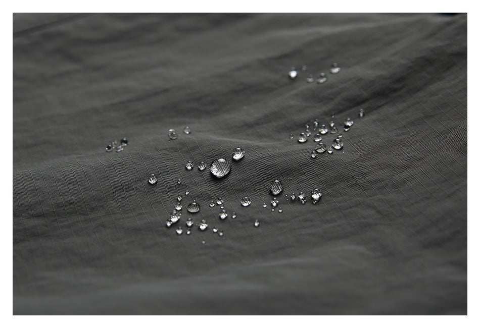 Close-up of water droplets beading on dark gray fabric.