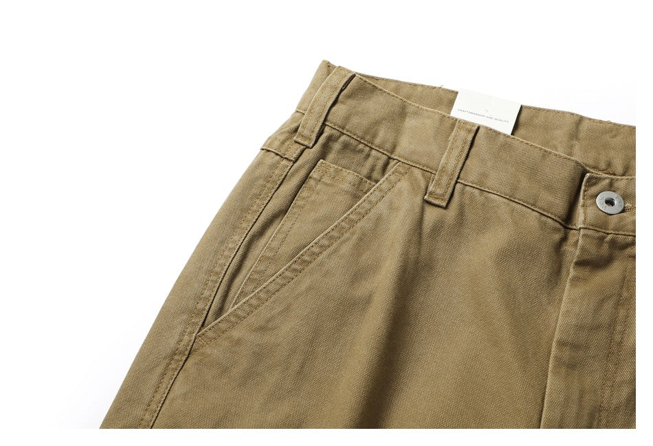 Close-up of the khaki trousers' waistband, belt loops, button and angled front pocket.