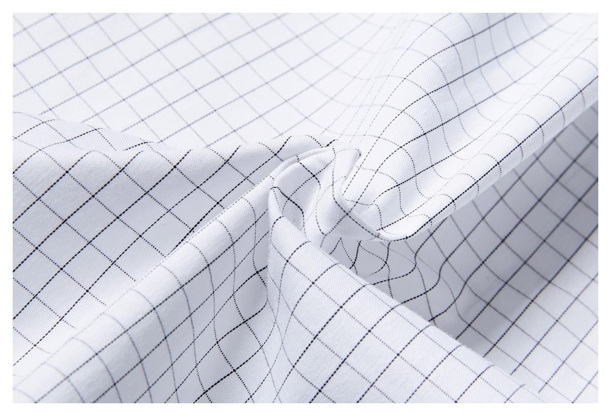 Close-up of white fabric with a fine black grid pattern, gathered to show its texture and drape.