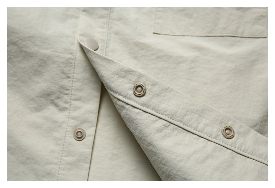 Close-up of the light beige jacket's snap fasteners and stitched front placket.