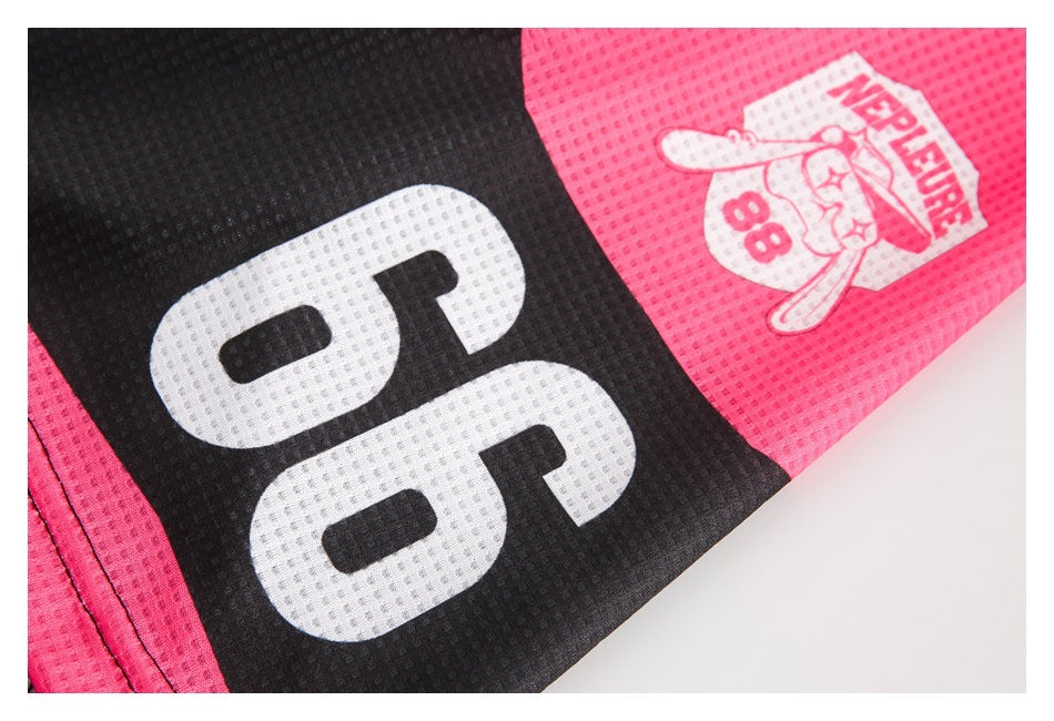 Close-up of a black-and-pink jersey with large white numerals and a small illustrated emblem.