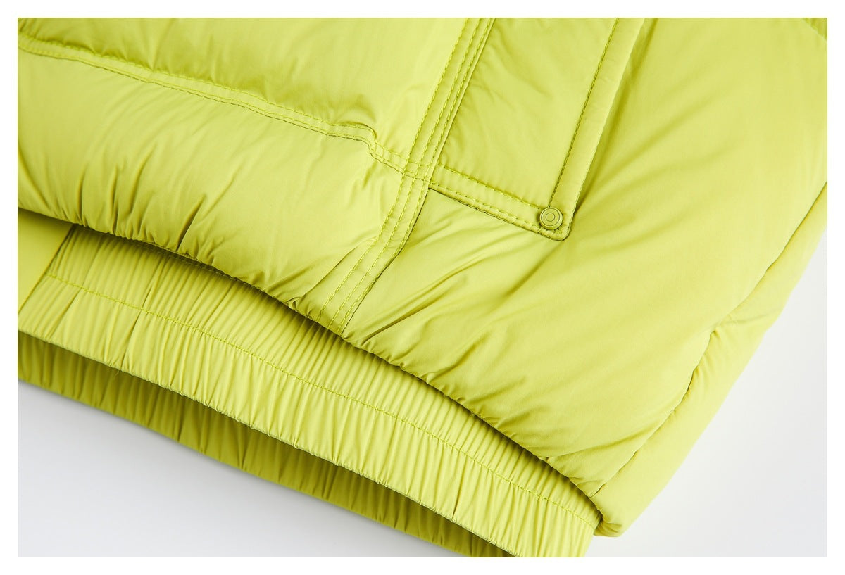 Close-up of the chartreuse padded jacket's gathered hem and a snap-fastened pocket flap.