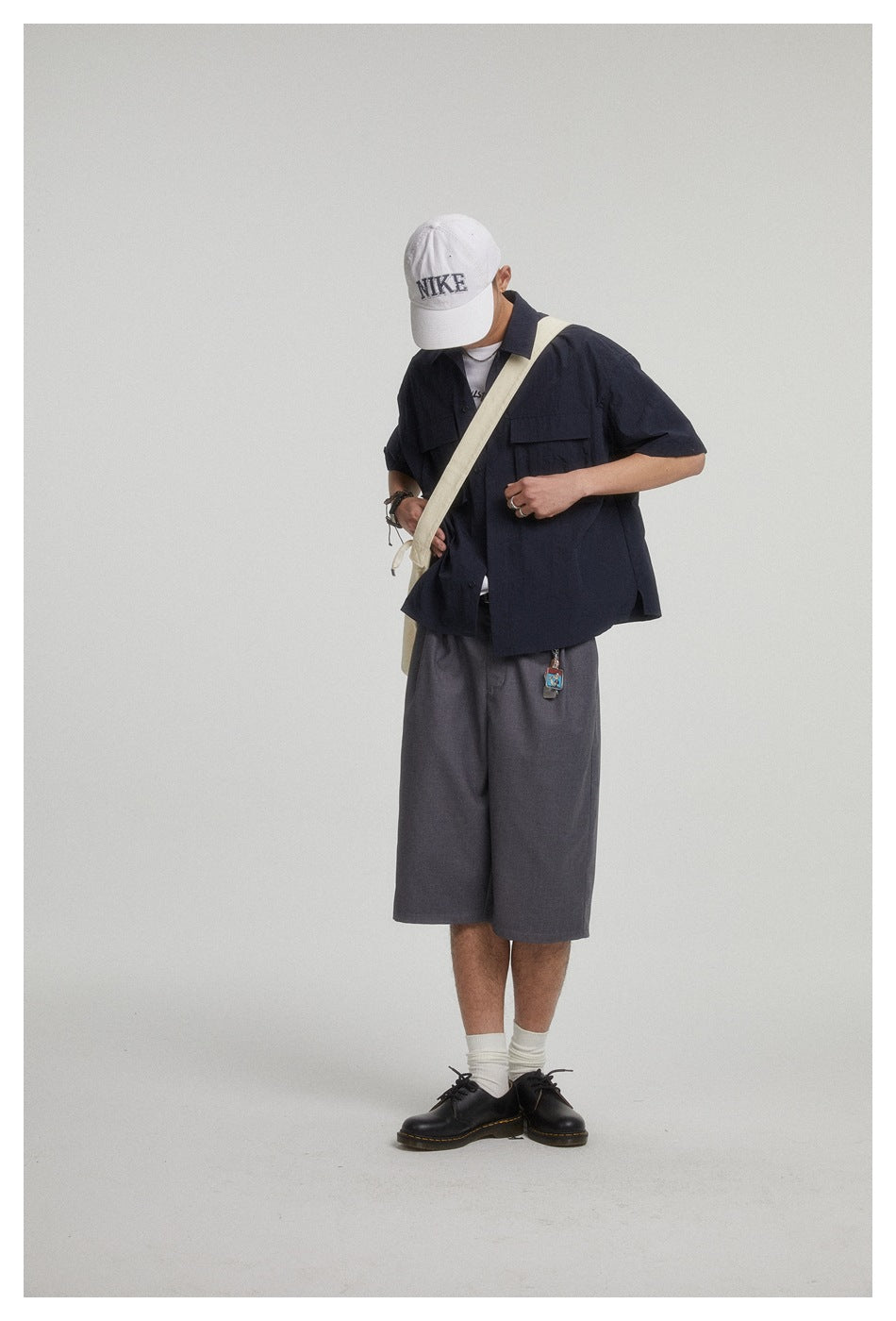 Model wearing a dark navy short-sleeve overshirt with flap pockets and charcoal wide-leg shorts.