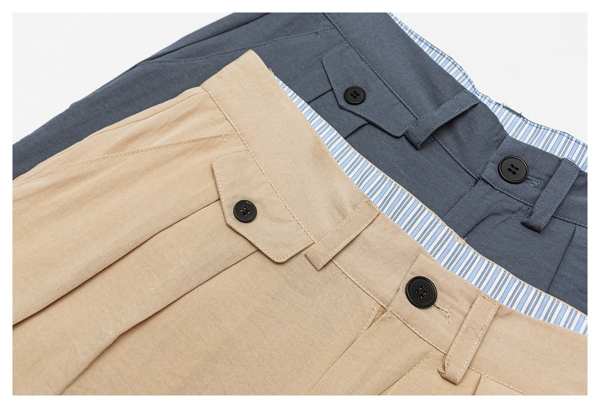 Close-up of tan and charcoal trousers with black buttons, belt loops, and blue striped inner waistbands.