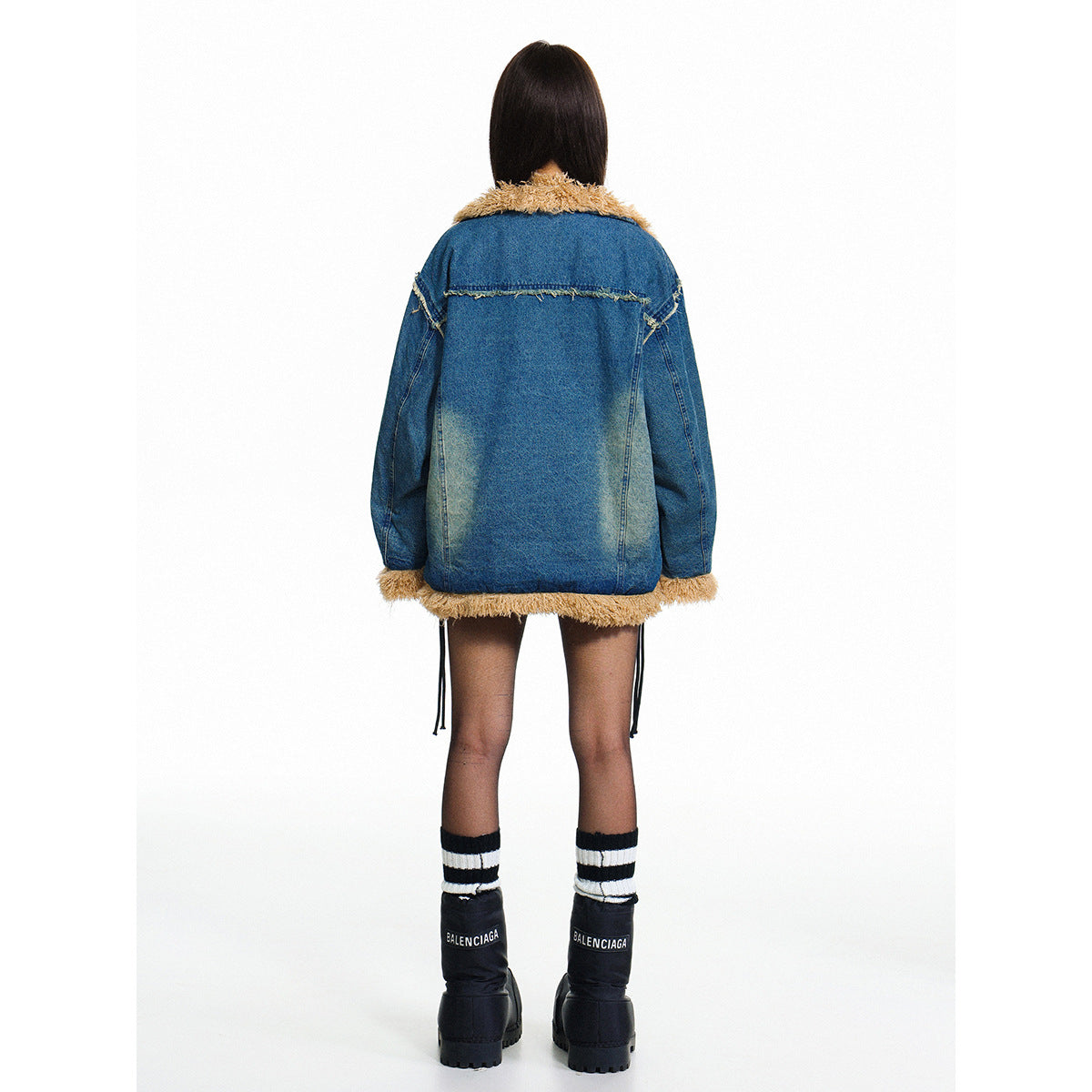 Rear view of a model wearing a blue denim jacket with a tan fuzzy collar, cuffs and hem.