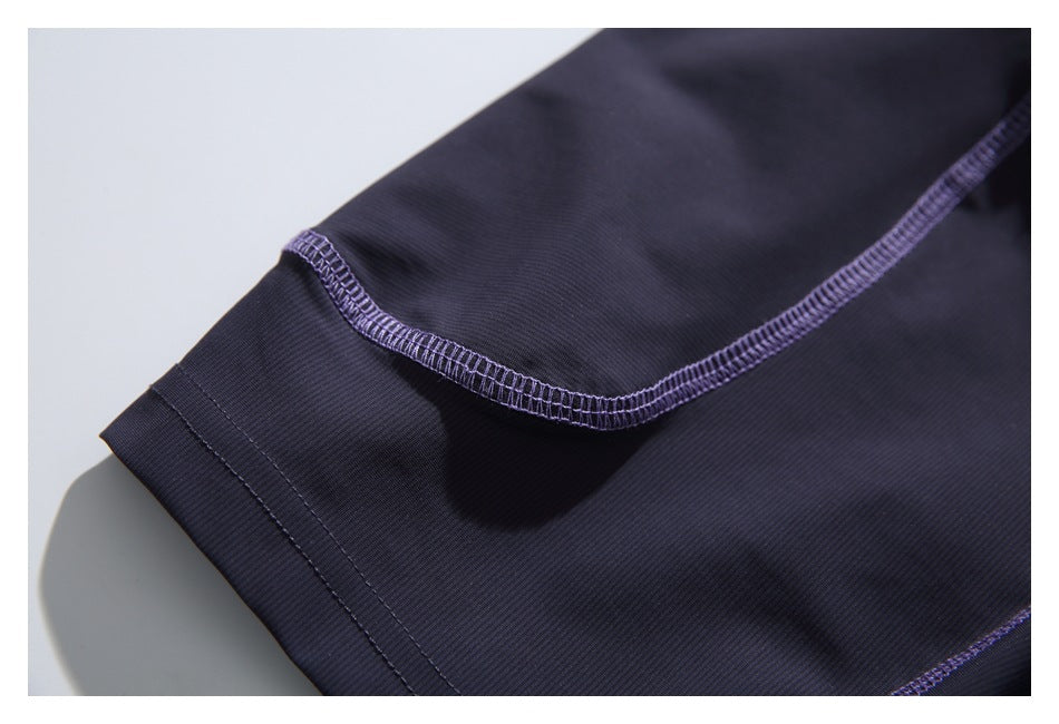 Close-up of the dark navy T-shirt sleeve hem and curved purple overlock seam.