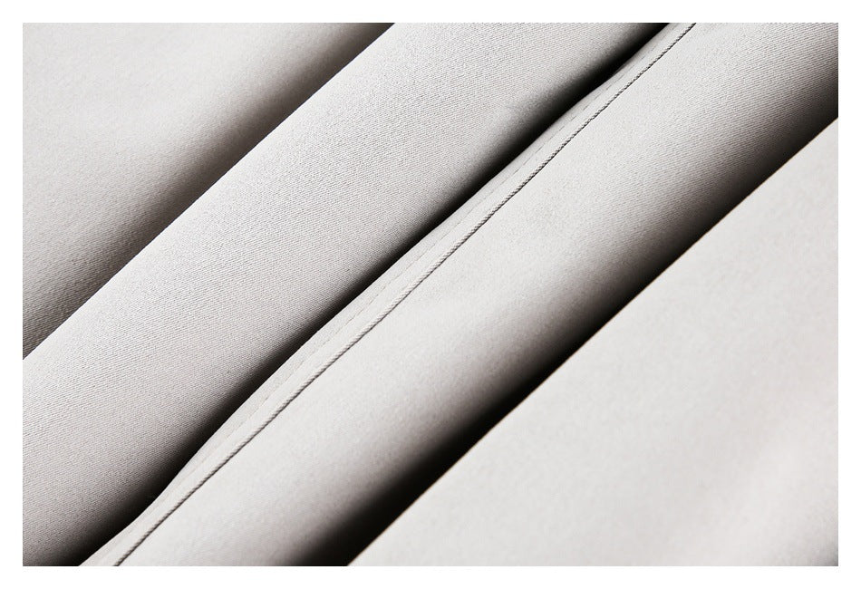 Close-up of a long stitched seam between folds of pale gray-beige garment fabric.