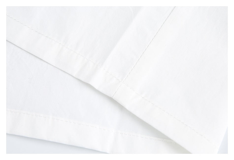 Close-up of white garment fabric showing intersecting stitched hems and folded edges.