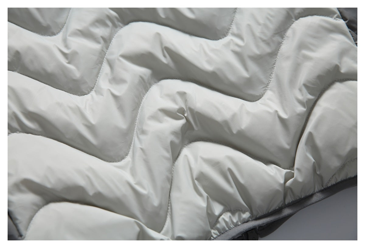Close-up of the light gray padded jacket's wavy stitched quilting and dark hem trim.