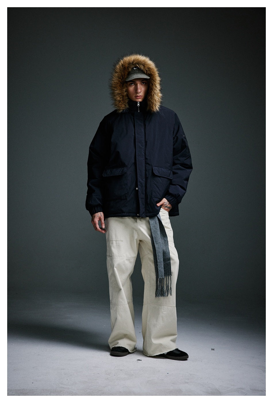 Full-length front view of a model wearing a dark navy fur-trim hooded jacket.