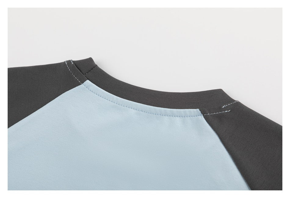 Close-up of the back neckline of a light blue and charcoal raglan T-shirt.