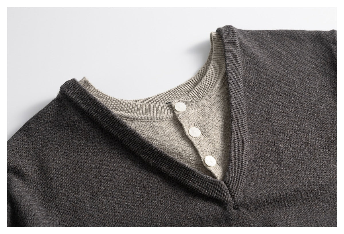 Close-up of a charcoal sweater's V-neck trim layered over a taupe knit neckline with three white buttons.