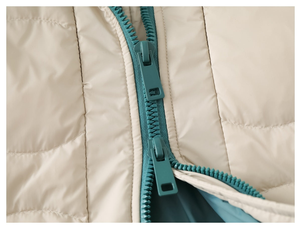 Close-up of a cream quilted garment with a teal two-way zipper and large pulls.