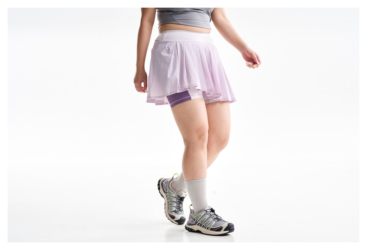 Cropped view of a woman wearing a lilac pleated skort over fitted shorts, with white knee socks and athletic shoes.