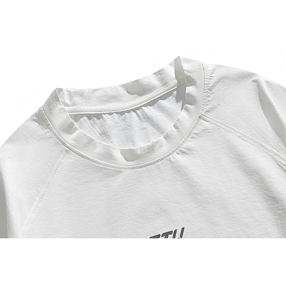 Close-up of a white T-shirt's crew neck and shoulder seams, with part of a dark chest graphic visible.