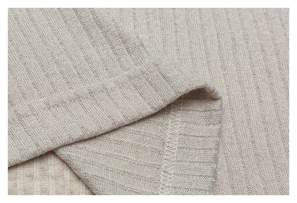 Close-up of a folded beige knit garment edge with visible stitching and subtle vertical stripes.