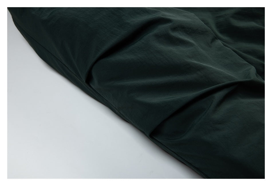 Close-up of dark green garment fabric showing folds and stitching.