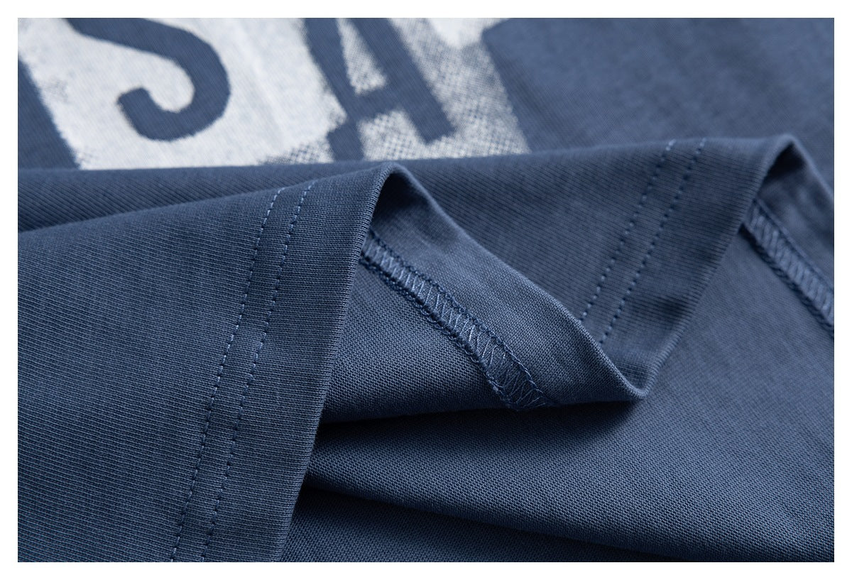 Close-up of a folded sleeve cuff and overlocked seam on the slate-blue T-shirt.