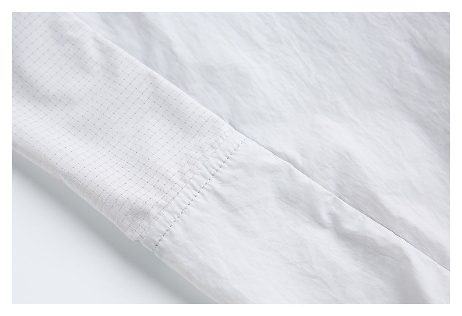 Close-up of a light gray garment showing a seam between smooth and fine grid-patterned panels.