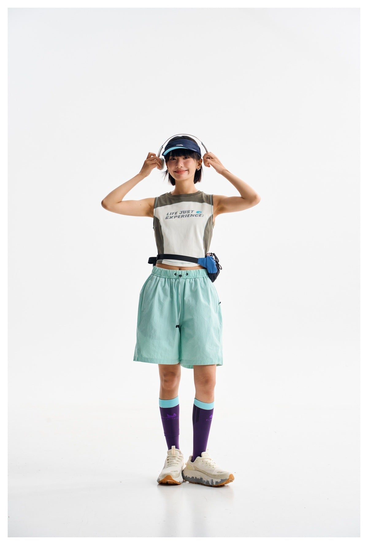 Model wearing a color-block sleeveless crop top and mint-green drawstring shorts, facing forward.