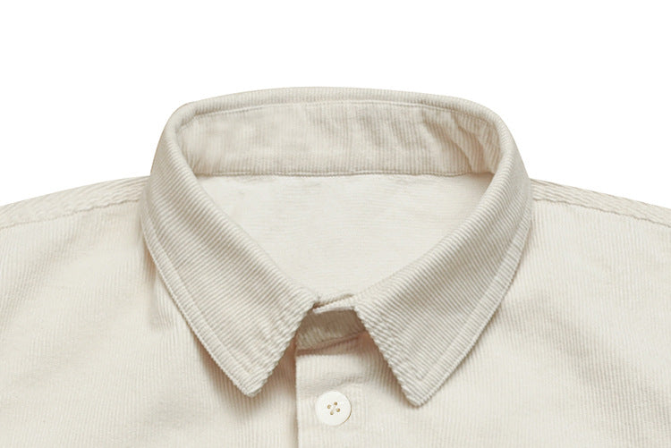 Close-up of a cream ribbed shirt's pointed collar and top button.