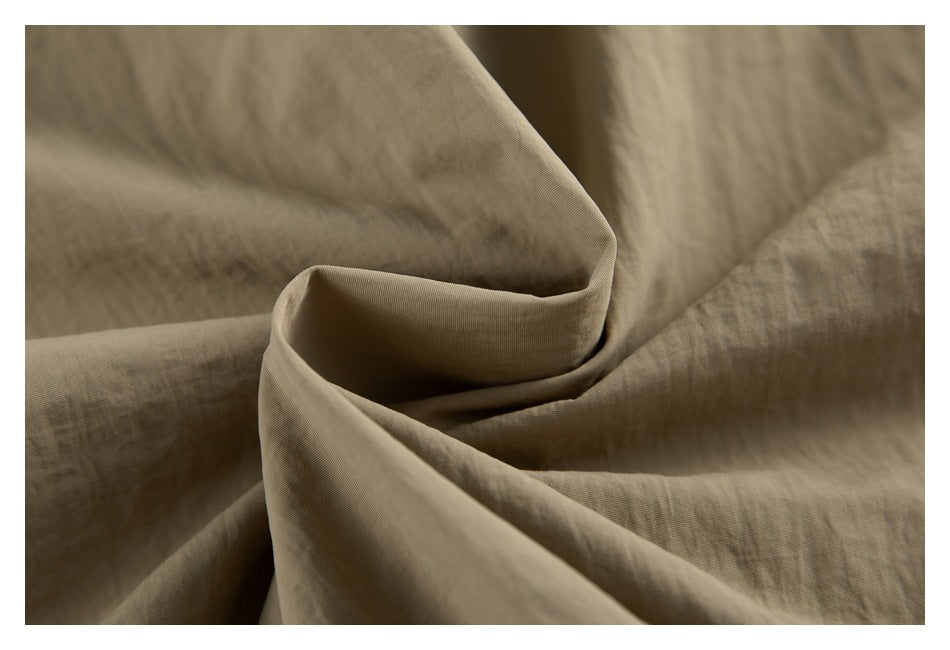 Extreme close-up of the tan jacket fabric folded to show its surface and drape.