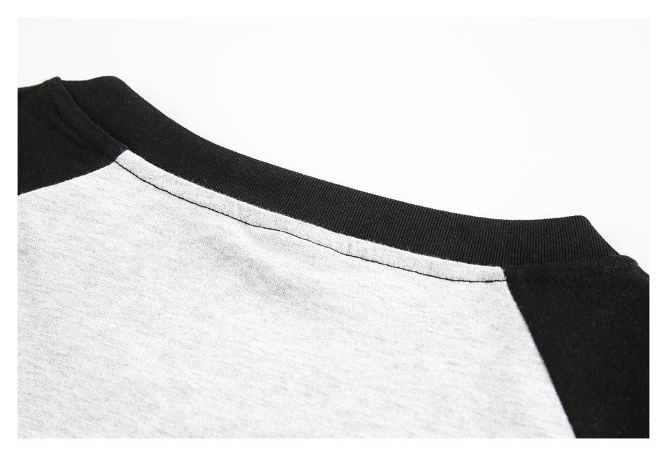 Close-up of a heather gray raglan shirt with black shoulders and a ribbed black crew neckline.