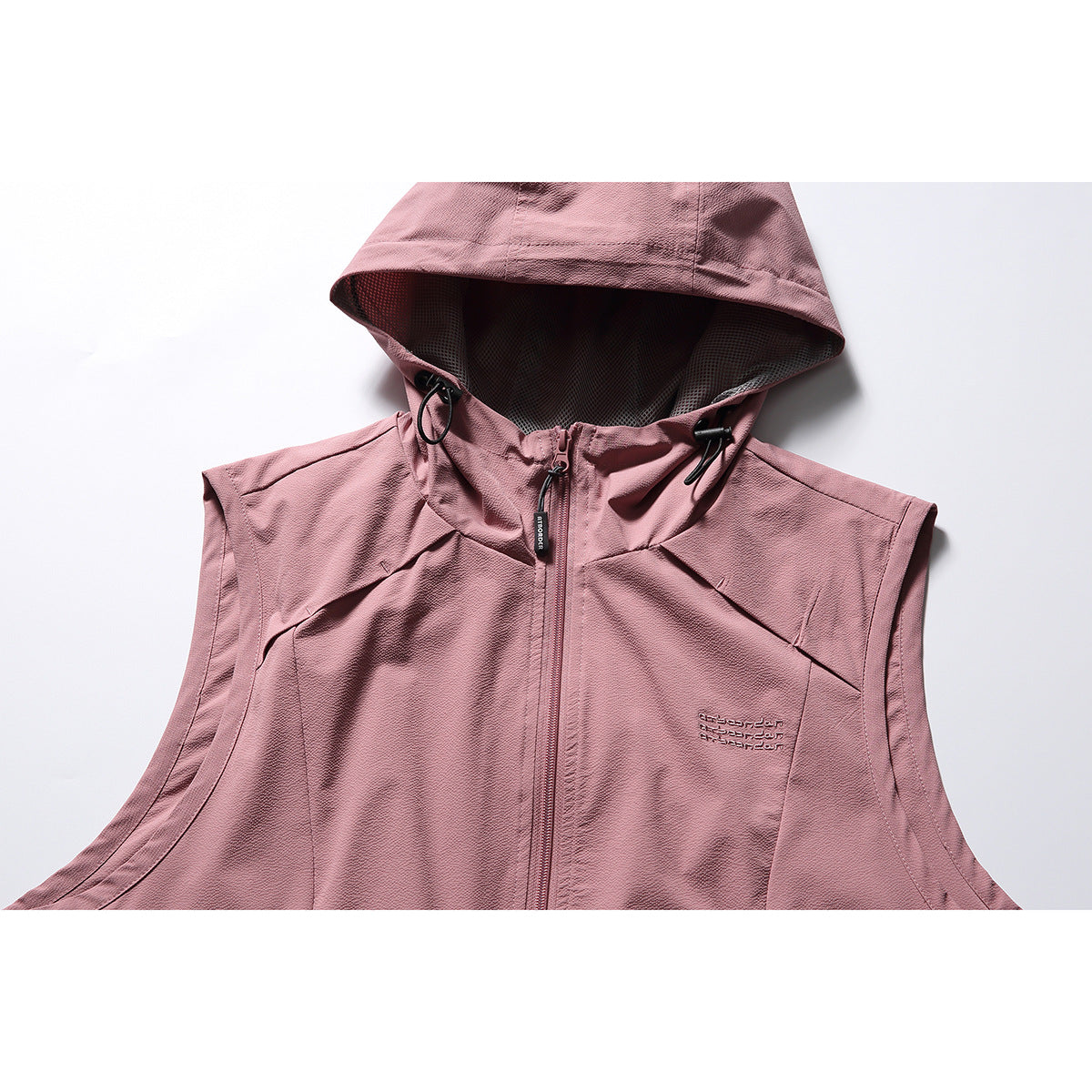 Close-up of a dusty rose sleeveless hooded vest showing its front zipper, drawcords, mesh-lined hood and chest embroidery.