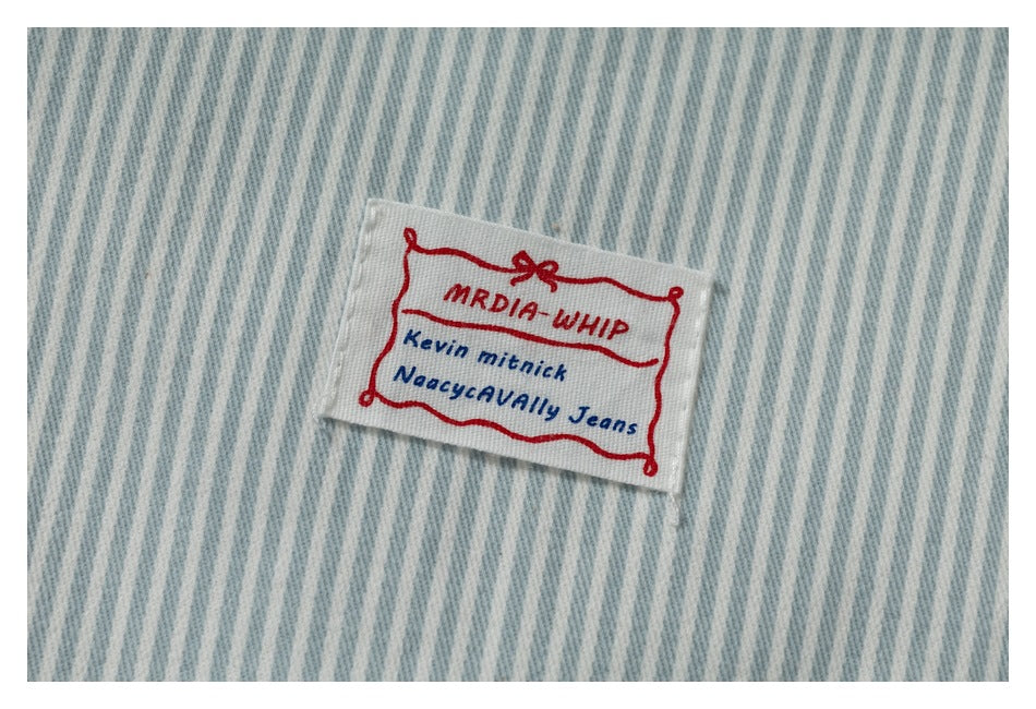Close-up of a sewn English-text label on the jacket's blue-and-white pinstriped fabric.