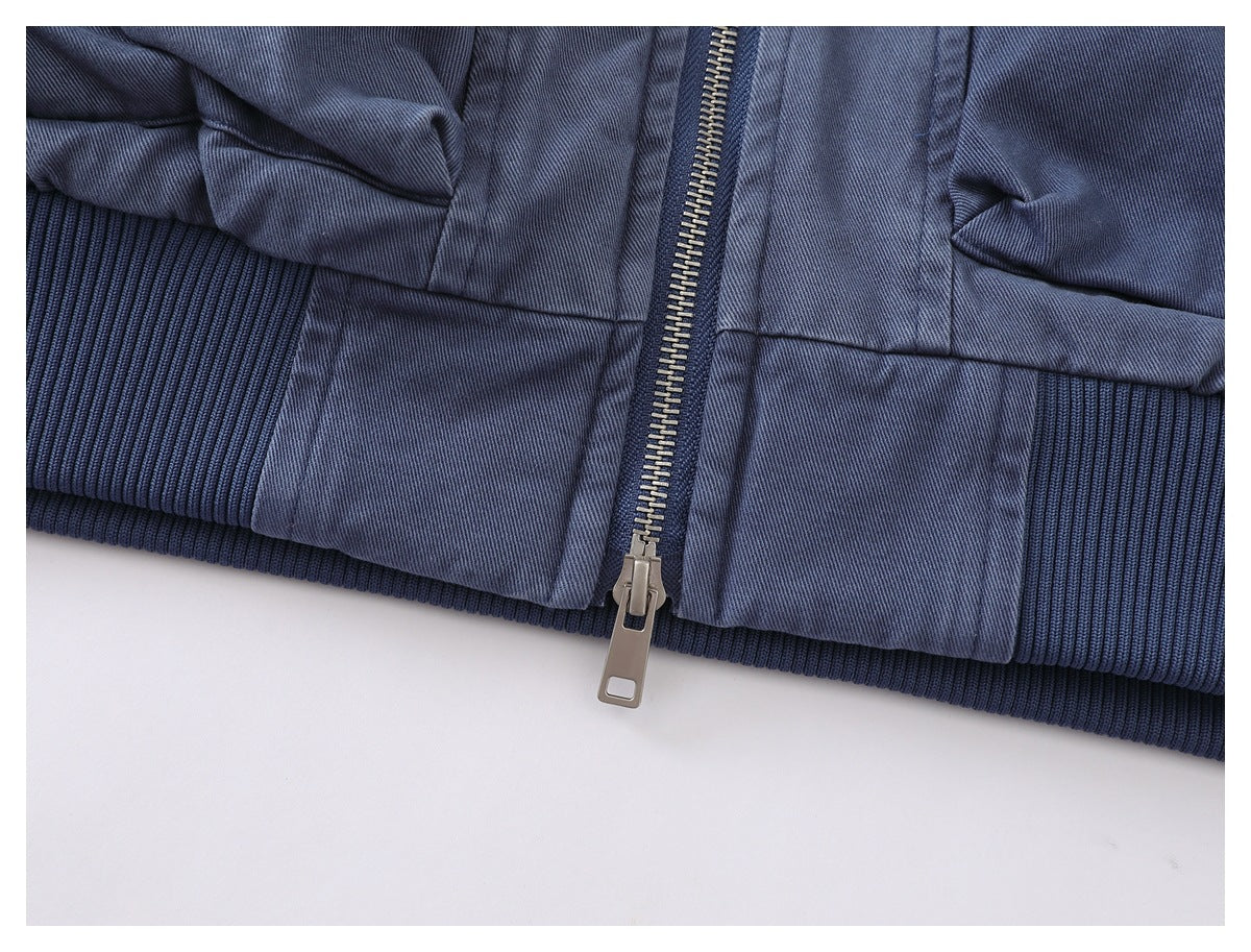 Close-up of the blue-gray jacket's ribbed hem and metal front zipper.
