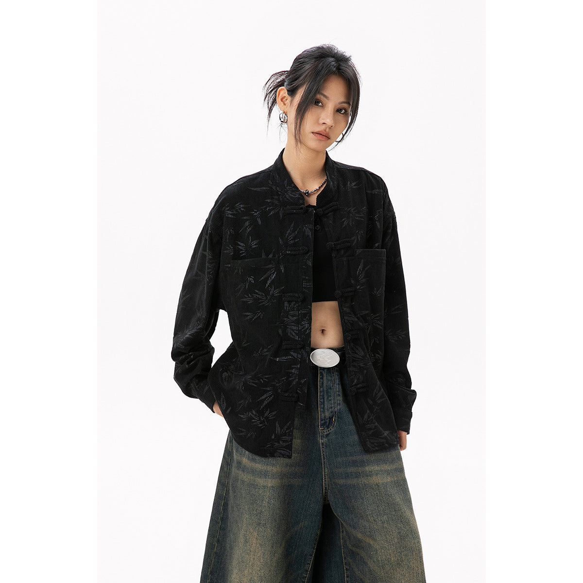 Model wearing a black bamboo-patterned jacket with frog closures and wide-leg jeans.