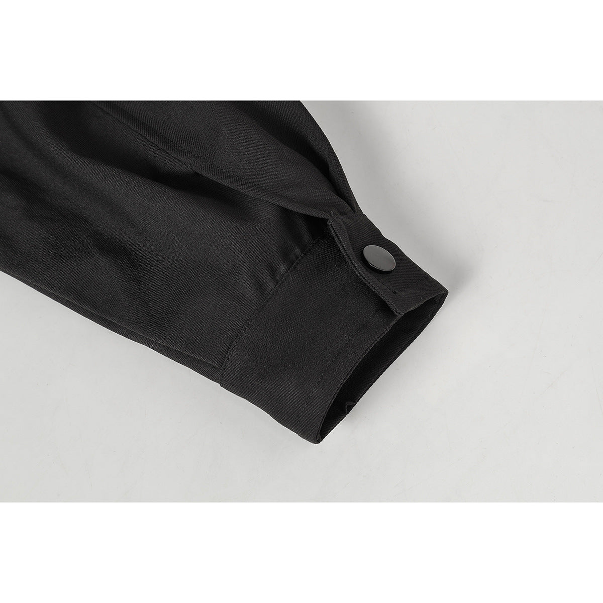 Close-up of a black jacket sleeve cuff with a snap-button tab.