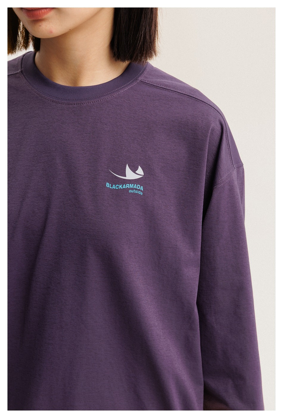 Close-up of a dark purple shirt with a light chest emblem and the words “BLACKARMADA outside.”
