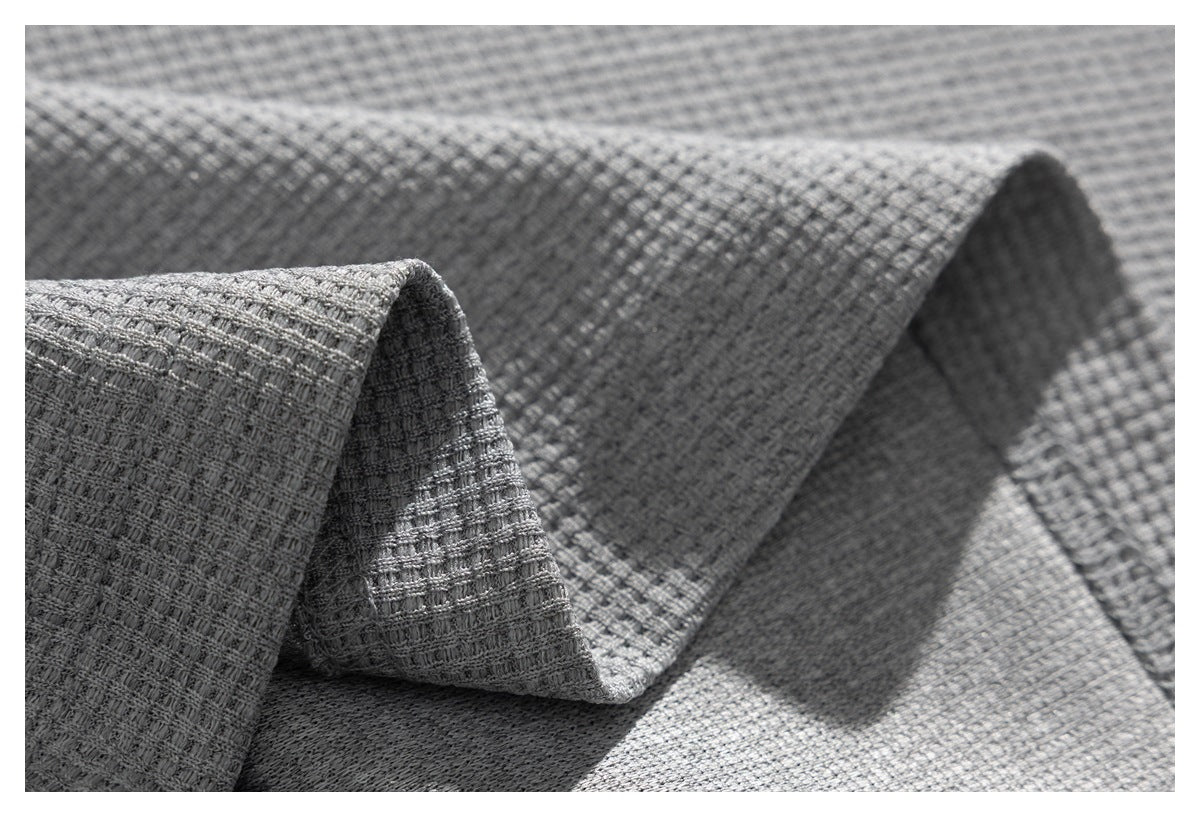 Extreme close-up of the light gray shirt's raised, grid-like fabric texture in soft folds.