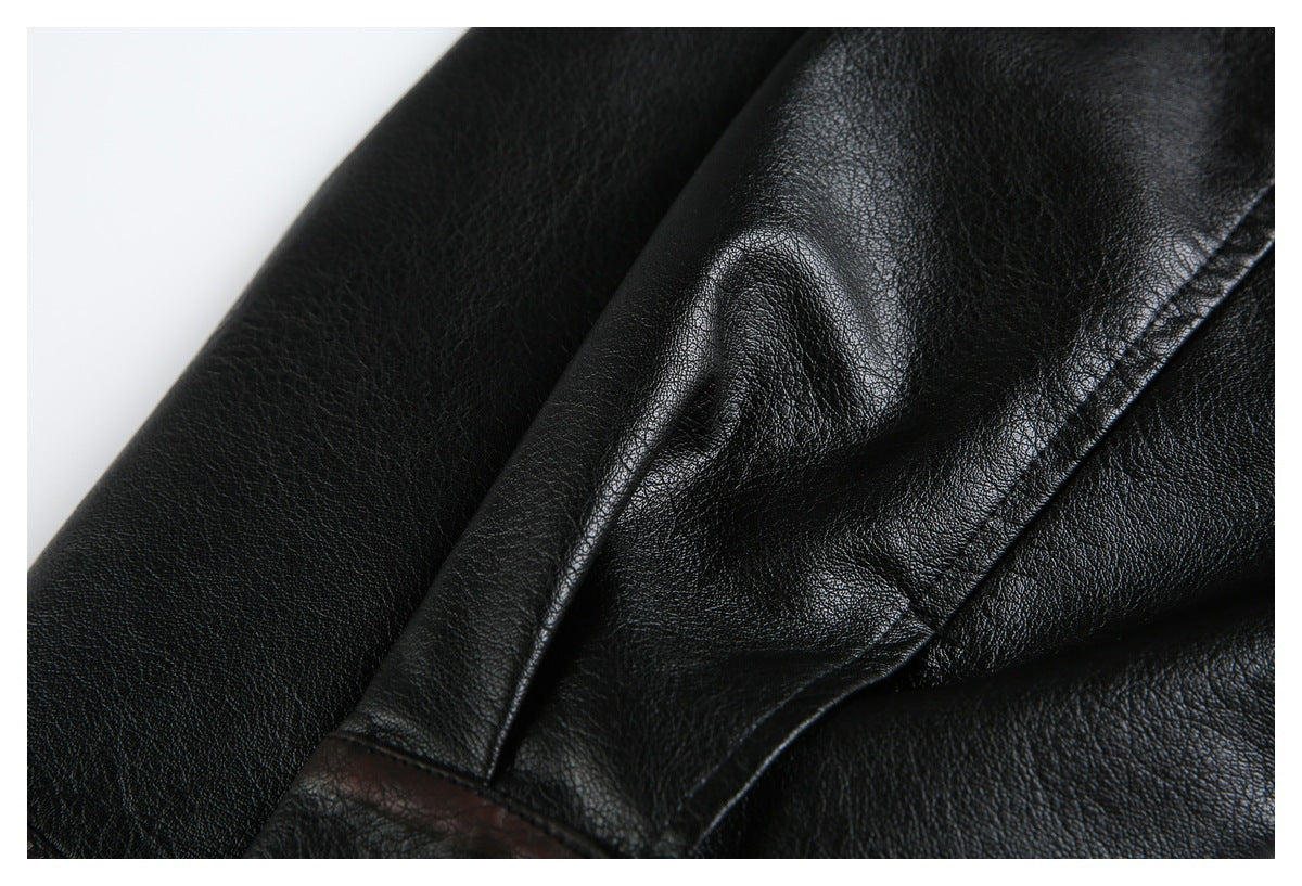 Close-up of black leather-look jacket panels with a raised seam and dark brown edge trim.
