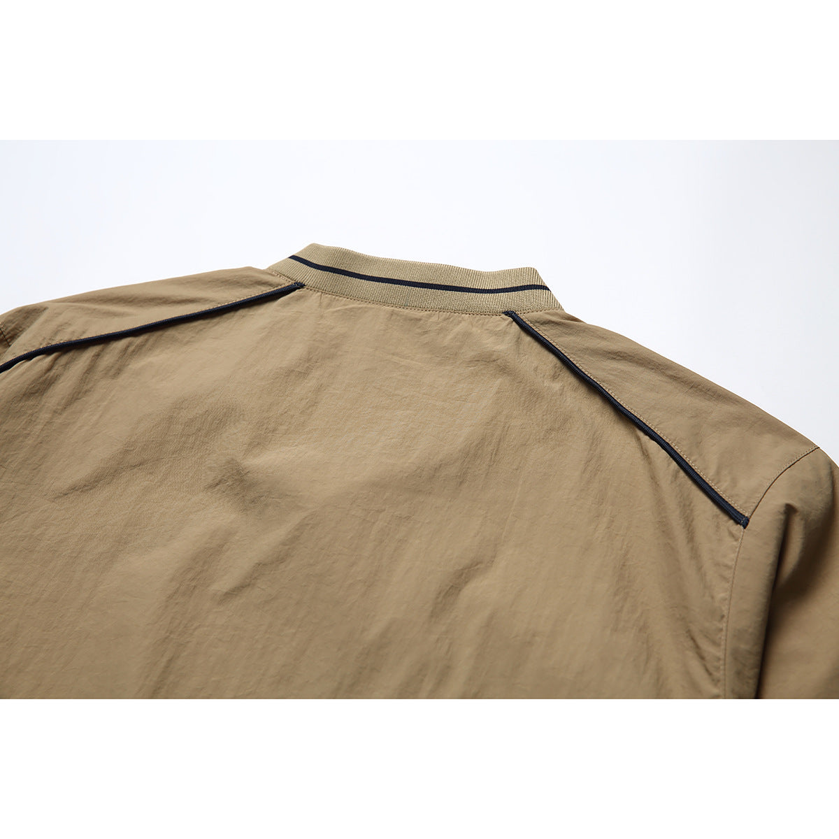 Close-up of the tan jacket back showing a striped ribbed collar and dark piping across the shoulders.