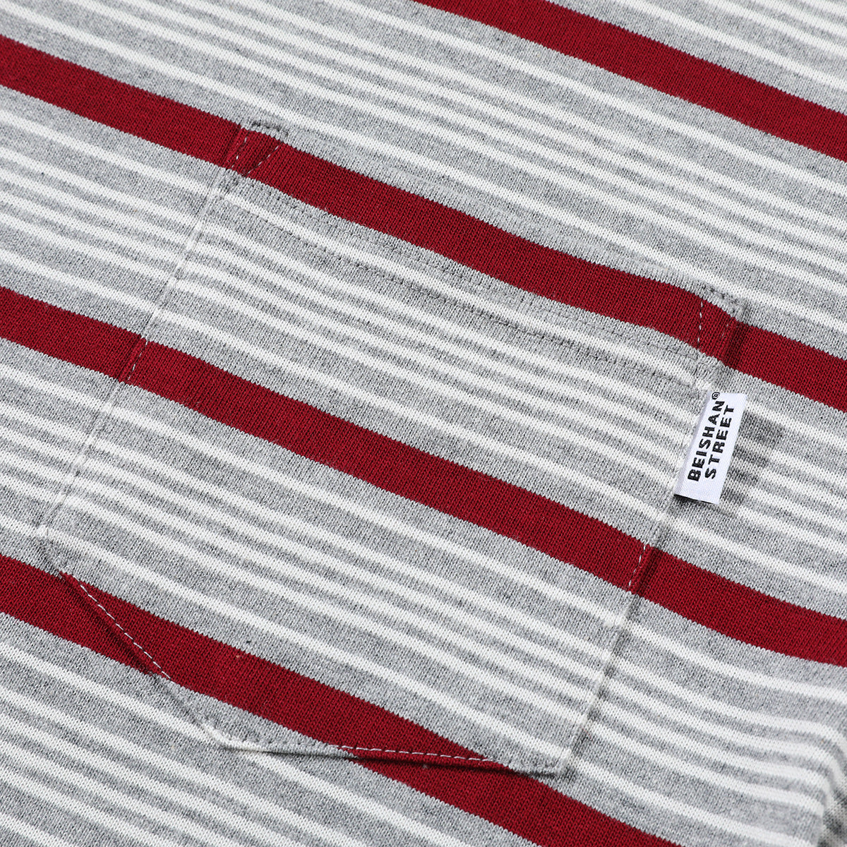 Close-up of a gray-and-white striped shirt pocket with burgundy stripes and a small sewn label.