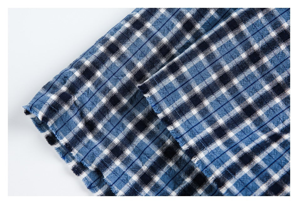 Close-up of blue, navy and white plaid fabric showing a folded, slightly frayed edge.