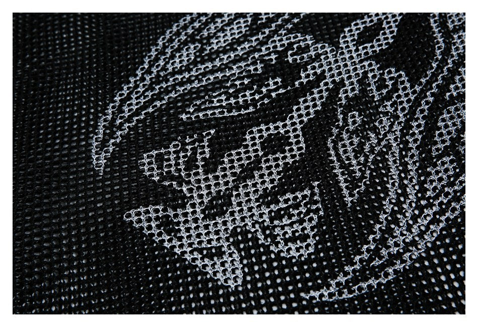 Close-up of black open-knit mesh with a white abstract pattern across the surface.