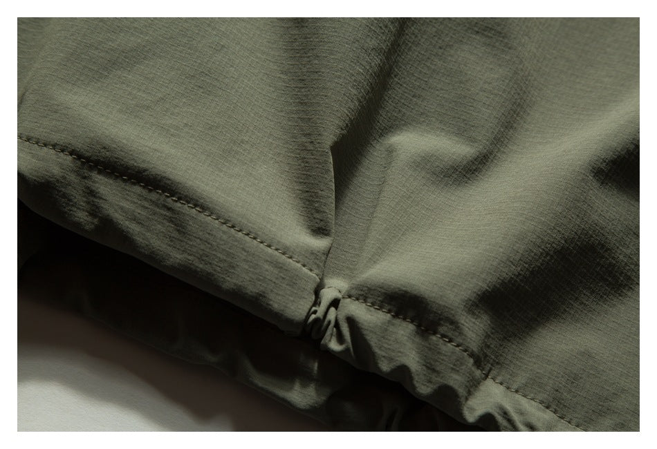 Close-up of an olive-green garment edge with stitching and gathered fabric at a seam.