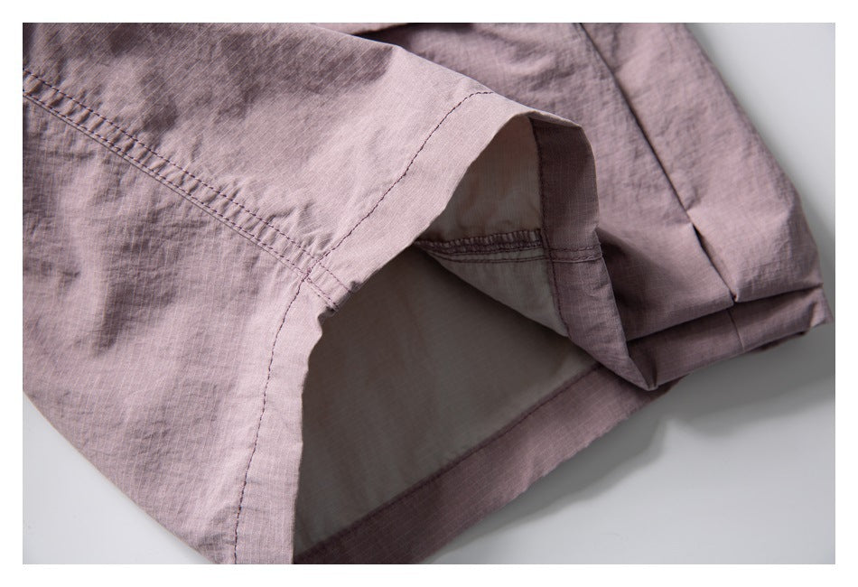 Close-up of the dusty mauve shorts' leg opening, stitching and pale inner lining.
