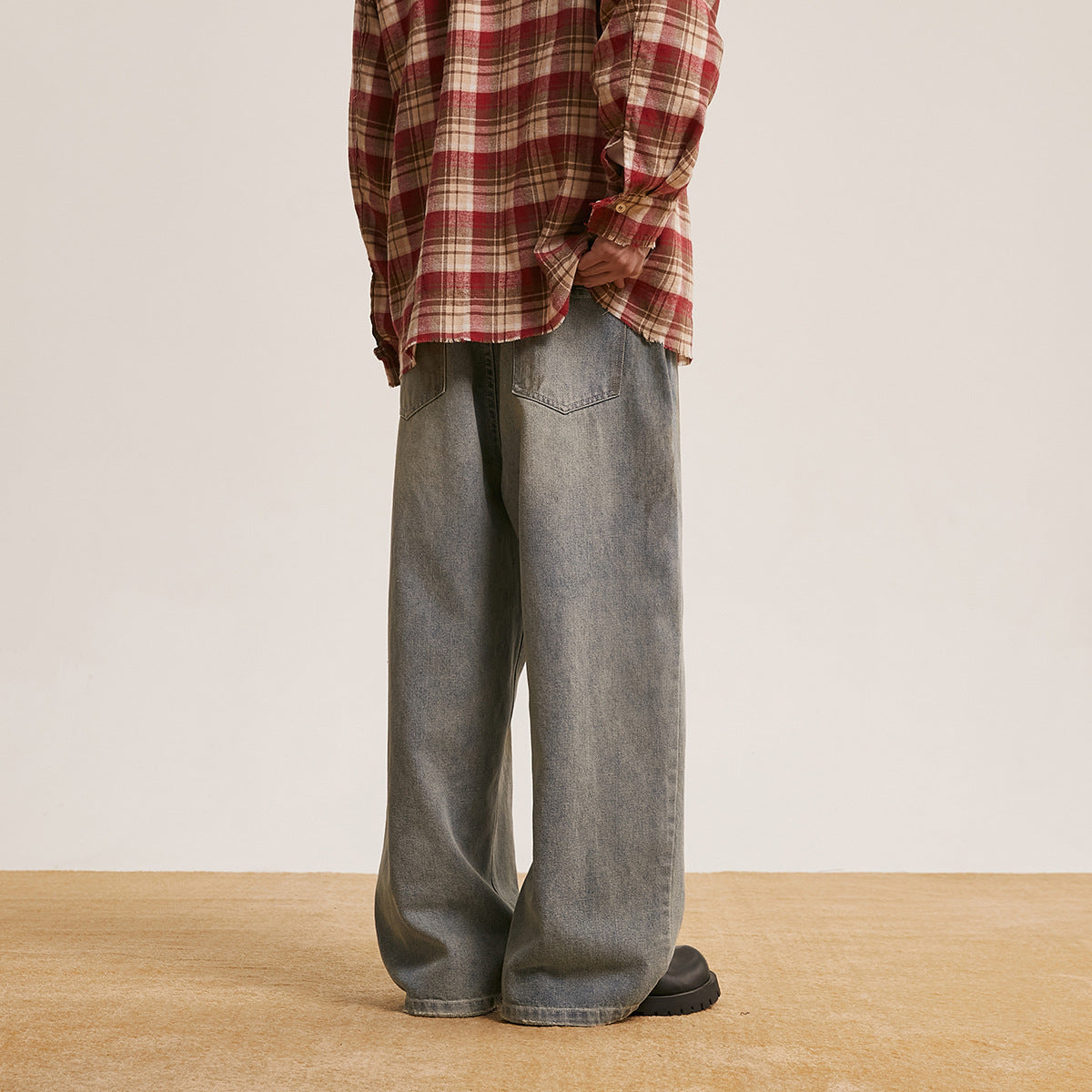 Model wearing loose gray washed jeans, shown from the back with two patch pockets.