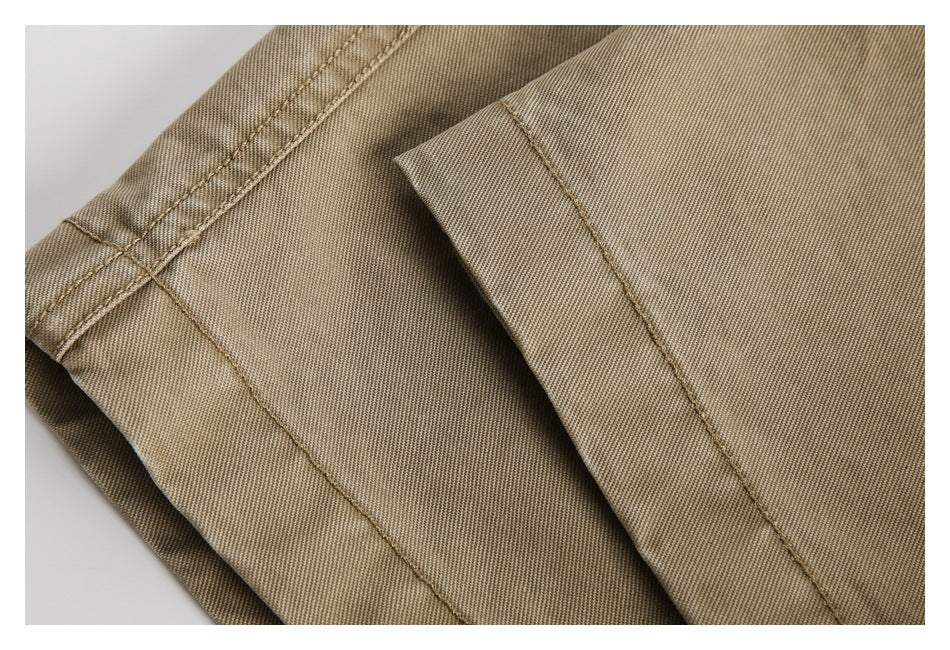 Close-up of tan trousers showing intersecting stitched seams and folded fabric.