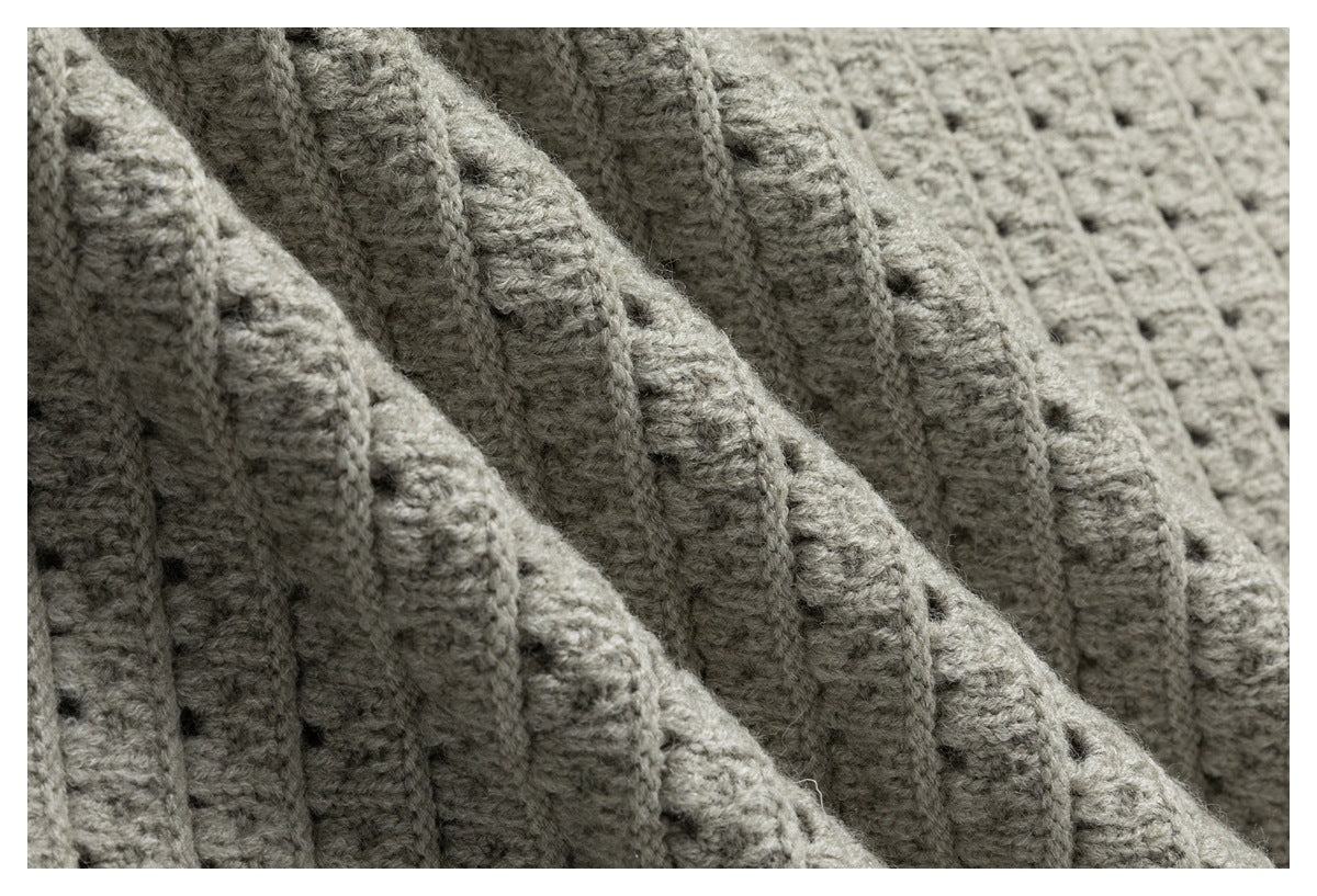 Macro view of folded light gray knit fabric, showing raised ribs and small stitch openings.