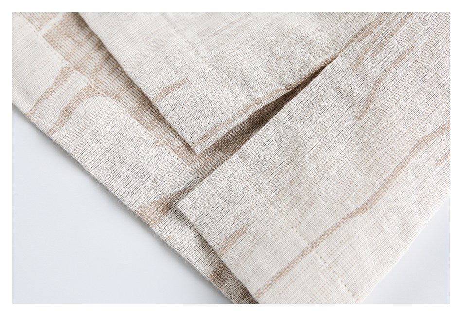 Layered edge and stitching on cream fabric patterned with tan abstract streaks.