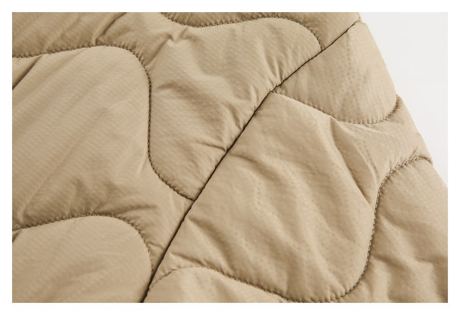 Close-up of beige quilted jacket fabric with curved stitched panels.